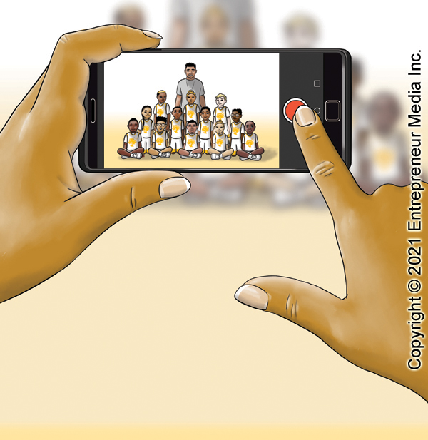 An illustration of someone taking a team photo using a cell phone.  Only the picture-taker's hands and phone are visible, with the team visible on the screen.  The actual team is out of focus in the distance.  